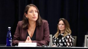 Image of Secretary Garcia speaking at a conference with a woman wearing polka dot sweater behind her.