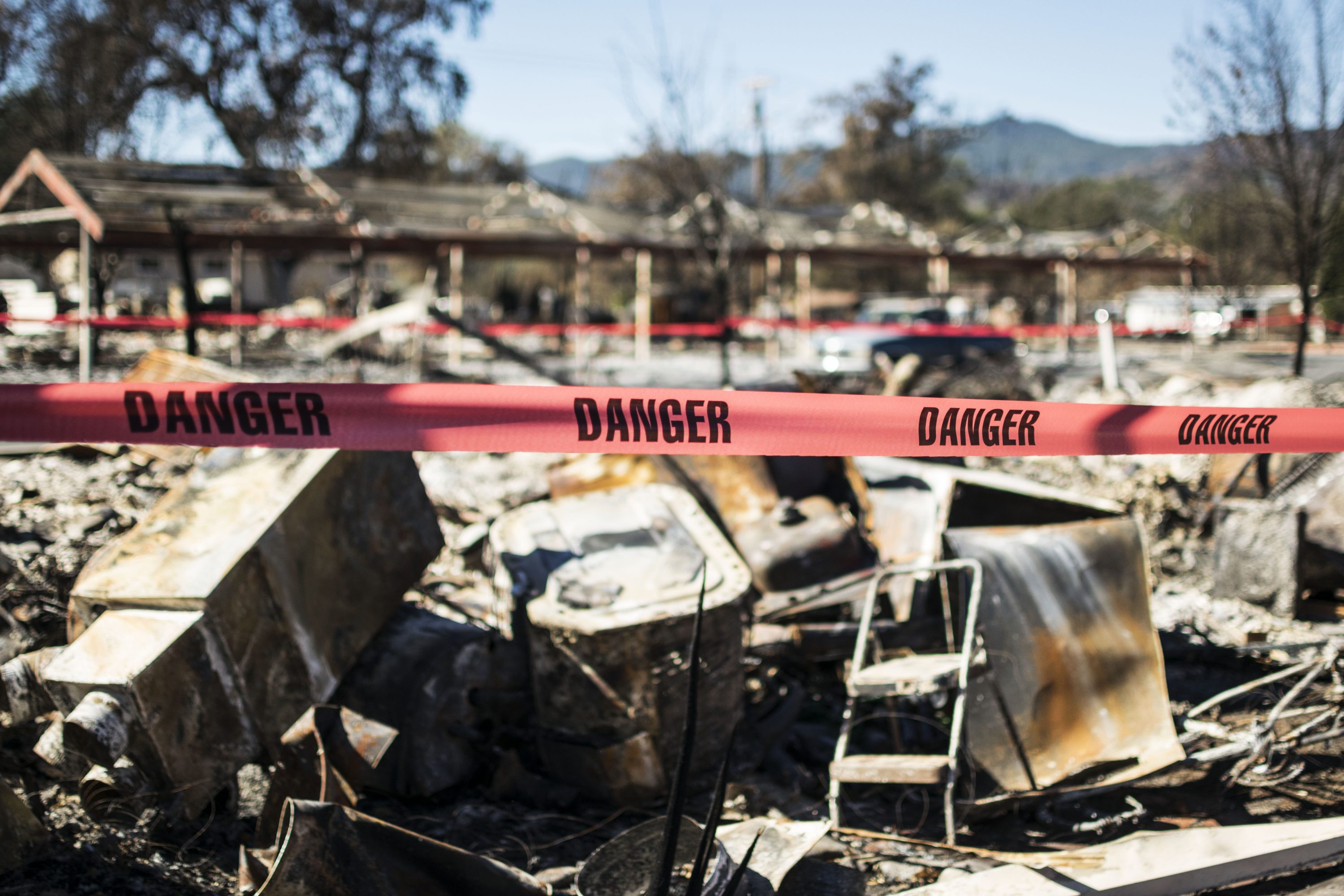 Photo: A strip of red caution tape that reads "Danger" warns against entering the area of burned debris seen in the background.