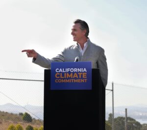 A photo of California Gov. Gavin Newsom at a podium with a sign that says. "California Climate Commitment."