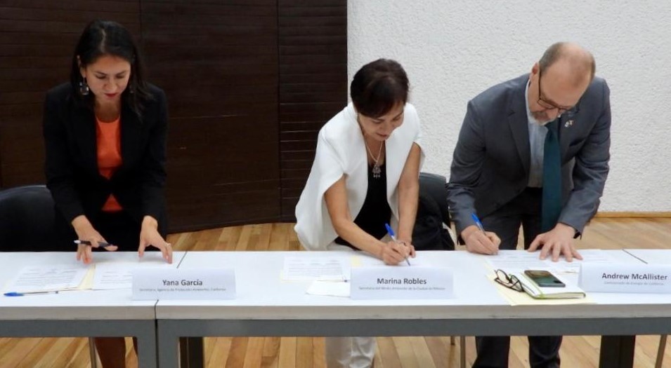A photo of three people signing an MOU.